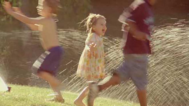 Girl runs through water sprinkler in Heinz Pourable Sunshine picnic