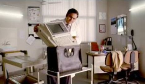 Doctor places large electrocardiograph in a bag in Ecomagination Backpack ad