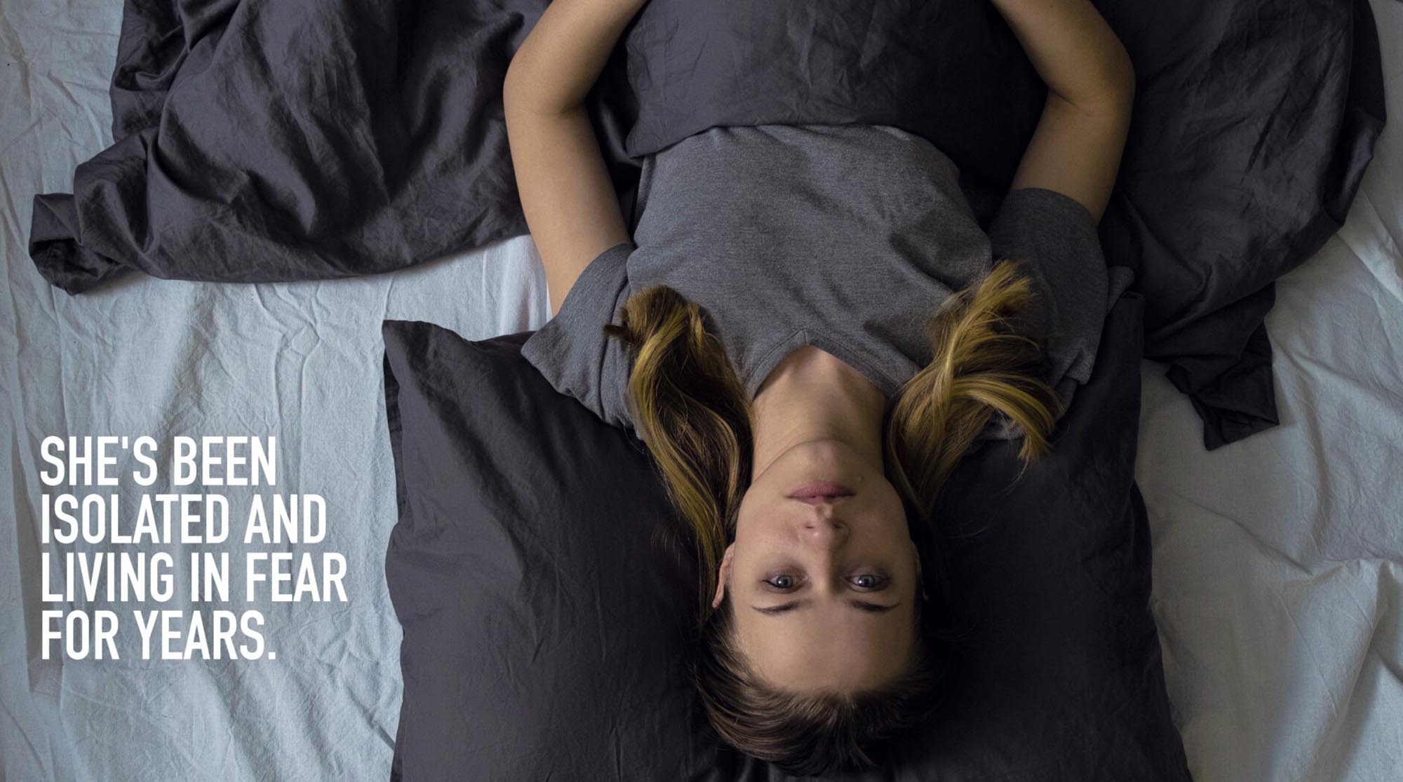 Woman lying on bed in Domestic Abuse print ad